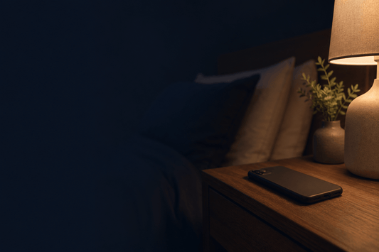 dside scene, a small lamp on low, an empty uncluttered surface, deliberately calm and sparse, no phone, no smartwatch, no tracker visible anywhere.
