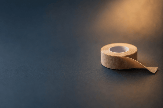 Image of a simple roll of tape resting on a plain, softly lit surface