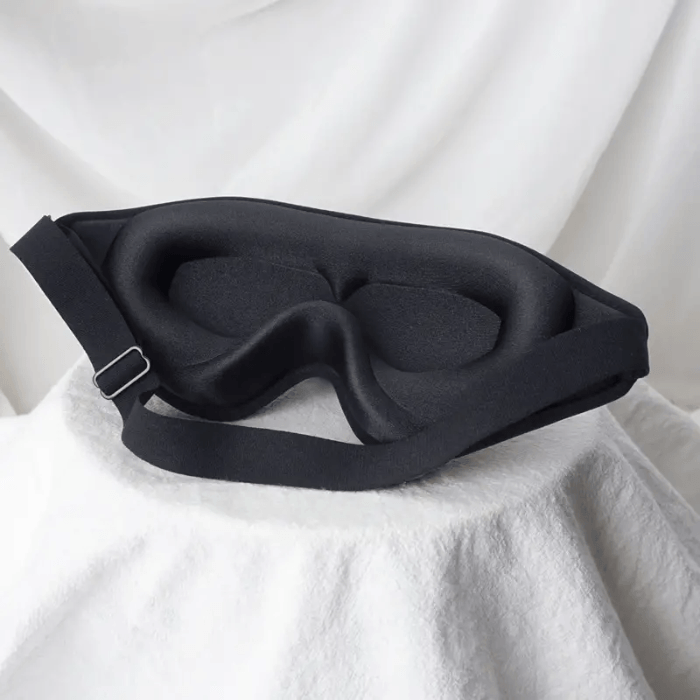 Black sleep mask on a white fabric background