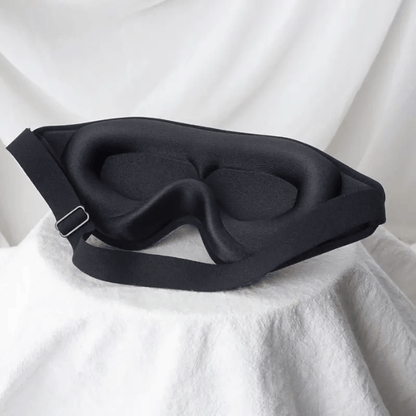 Black sleep mask on a white fabric background